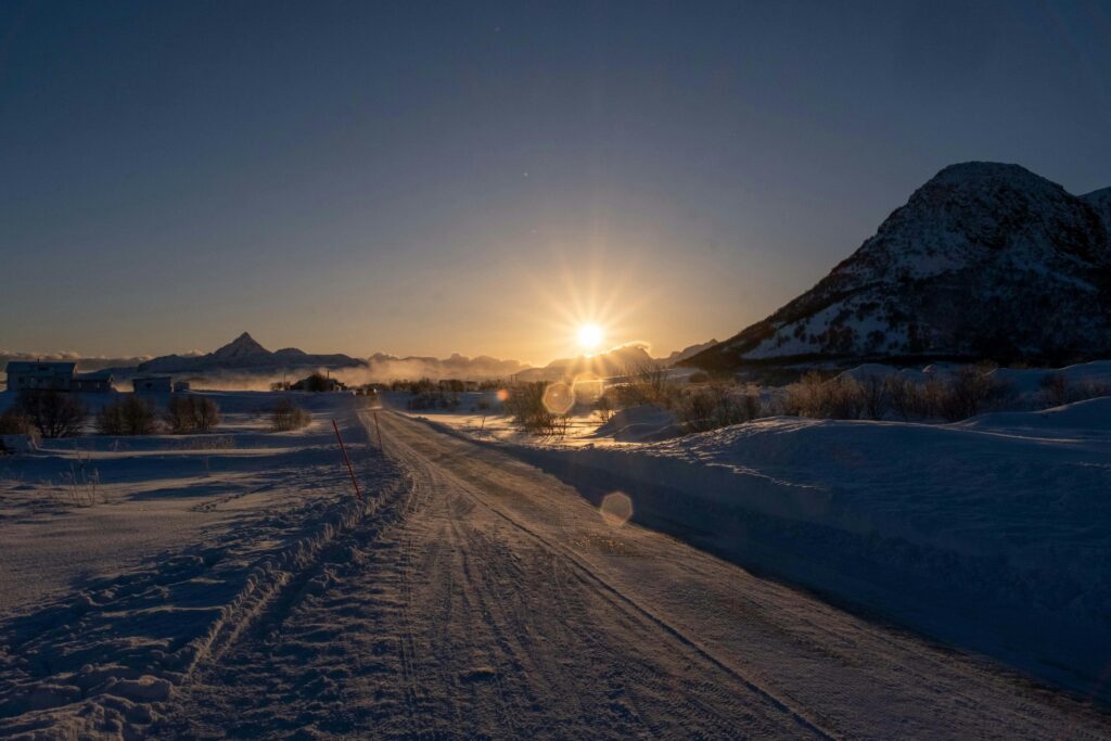 A beautiful winter sunset over a snowy mountain road, creating a tranquil and scenic view.