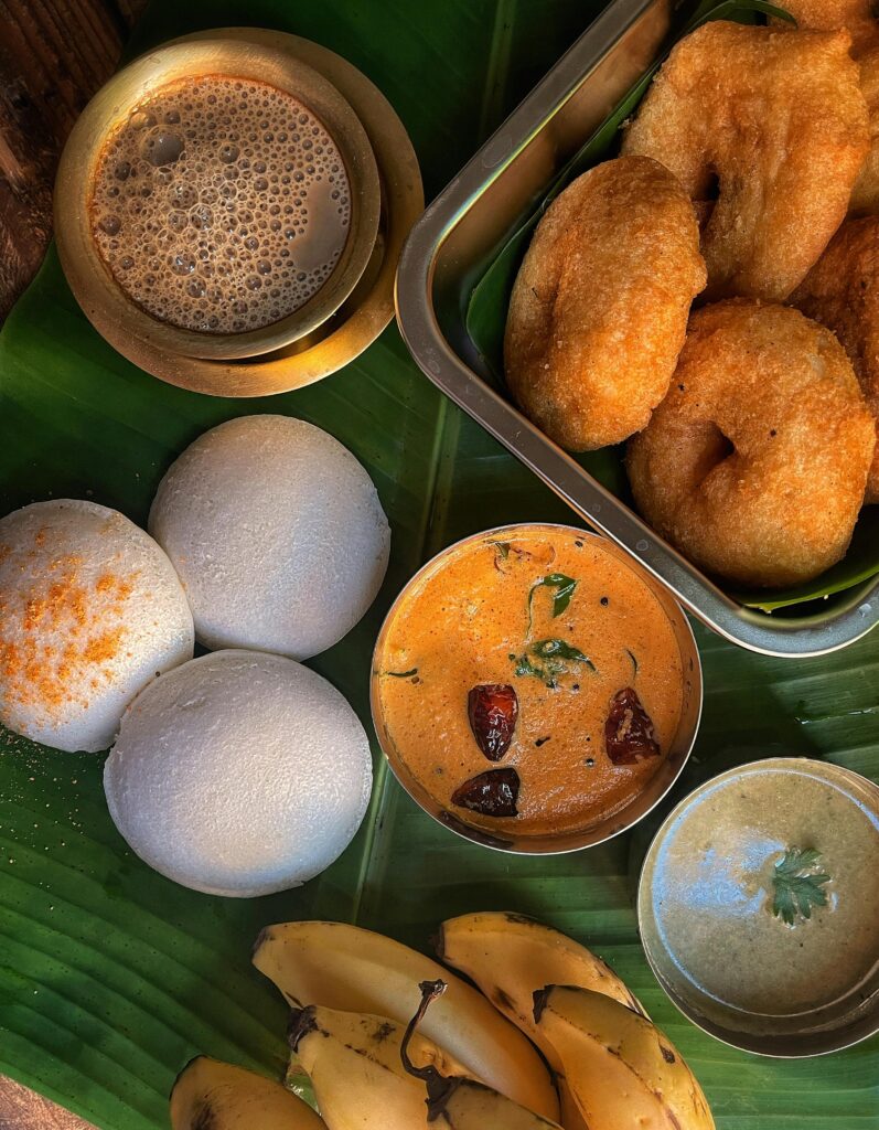Delicious South Indian breakfast with idli, vada, chutney, and coffee on banana leaf.