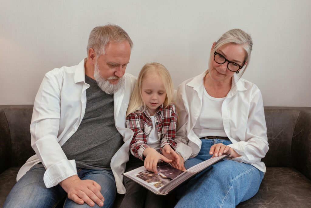 Elderly couple and granddaughter sharing memories while viewing a photo album together.