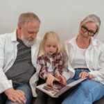 Elderly couple and granddaughter sharing memories while viewing a photo album together.