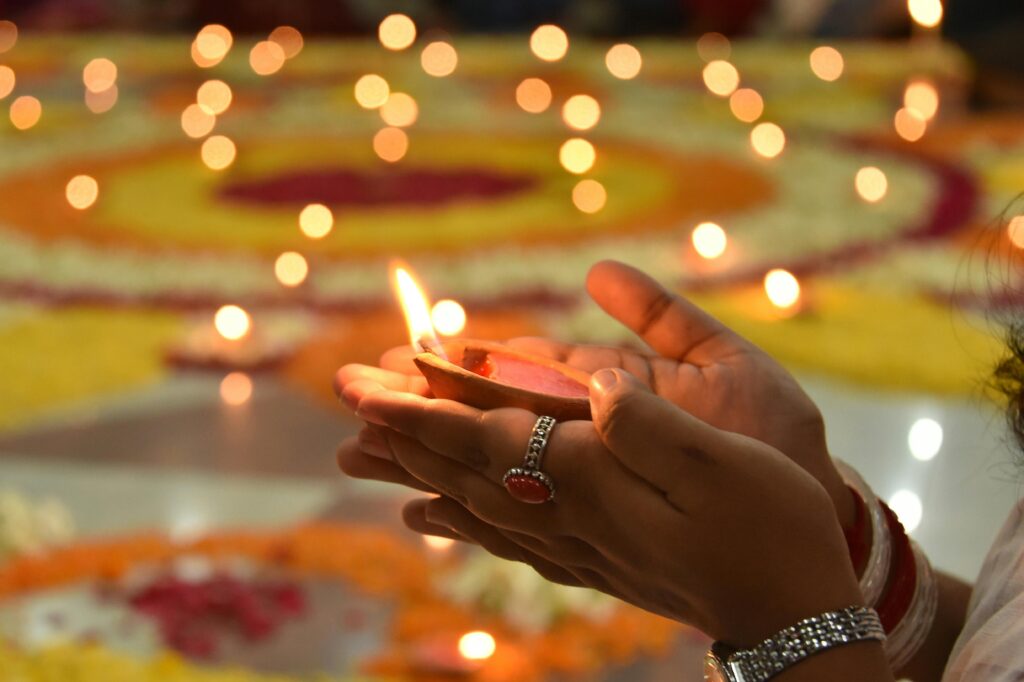 Close-up of a hand holding a lit candle during a religious ceremony surrounded by glowing lights.