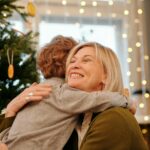 Loving embrace between a grandmother and grandson near a festive Christmas tree.