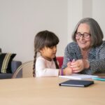 Elderly woman joyfully engaging with her grandchild, displaying bonding and happiness.