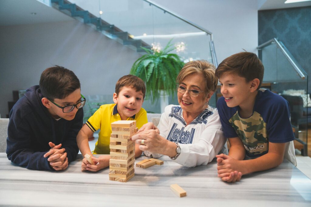A joyful family moment with grandma and grandsons playing Jenga indoors, capturing quality time together.