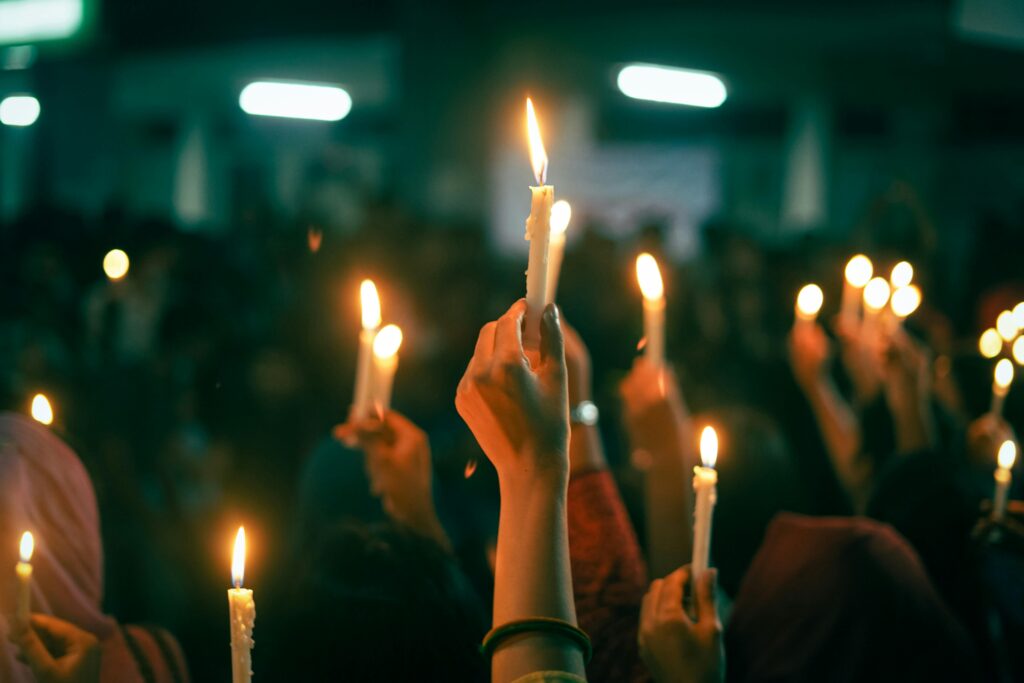 A crowd holds lit candles in a nighttime protest, symbolizing unity and hope.