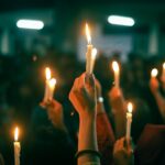 A crowd holds lit candles in a nighttime protest, symbolizing unity and hope.