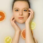 Relaxing portrait of a woman in a milk bath with citrus slices, embodying freshness and self-care.