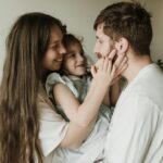 A cheerful family moment with parents and child embracing indoors.