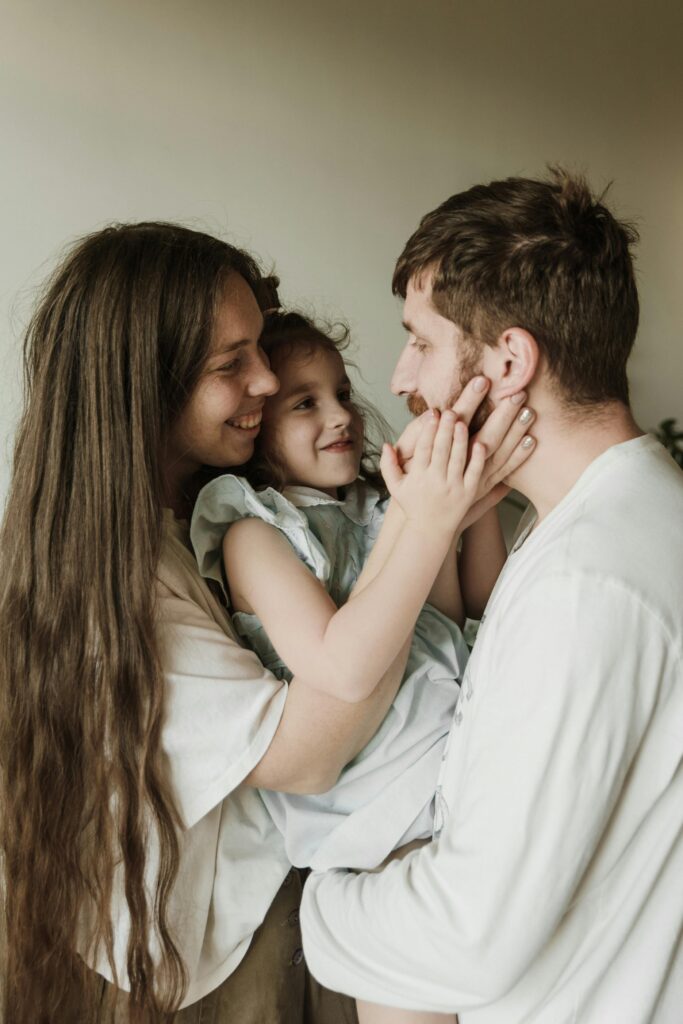 A cheerful family moment with parents and child embracing indoors.