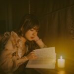 Serenity captured as a woman reads by candlelight in a dimly lit room.