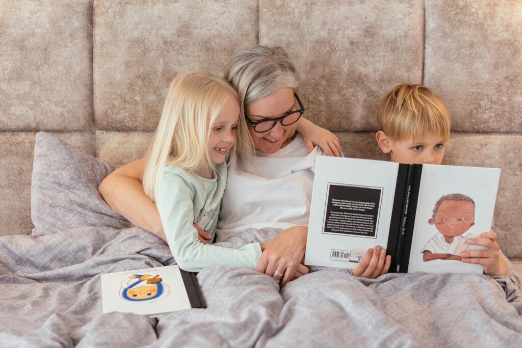 Grandmother reading a storybook with her grandchildren in a cozy bedroom setting, sharing smiles and bonding.