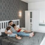 Father reading a book with his children in a comfortable and stylish bedroom setting.