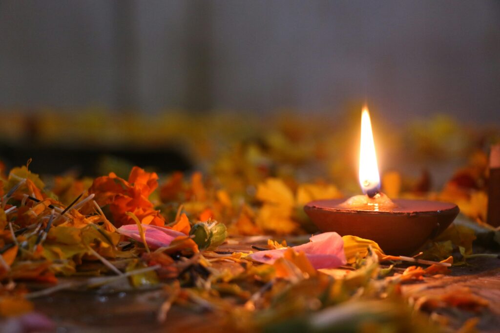 Close-up of a lit oil lamp surrounded by flower petals, creating a warm, festive atmosphere.