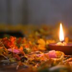 Close-up of a lit oil lamp surrounded by flower petals, creating a warm, festive atmosphere.
