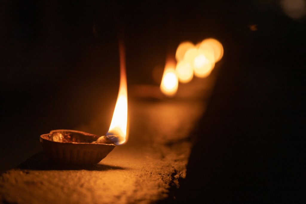 Close-up of a clay diya lamp with a vibrant flame symbolizing Diwali celebration.