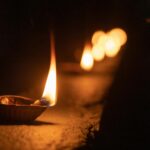 Close-up of a clay diya lamp with a vibrant flame symbolizing Diwali celebration.