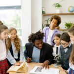 A diverse group of students learning with a teacher in a bright classroom setting.