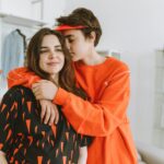 A touching moment of a teenage boy hugging his mother in a cozy indoor setting.