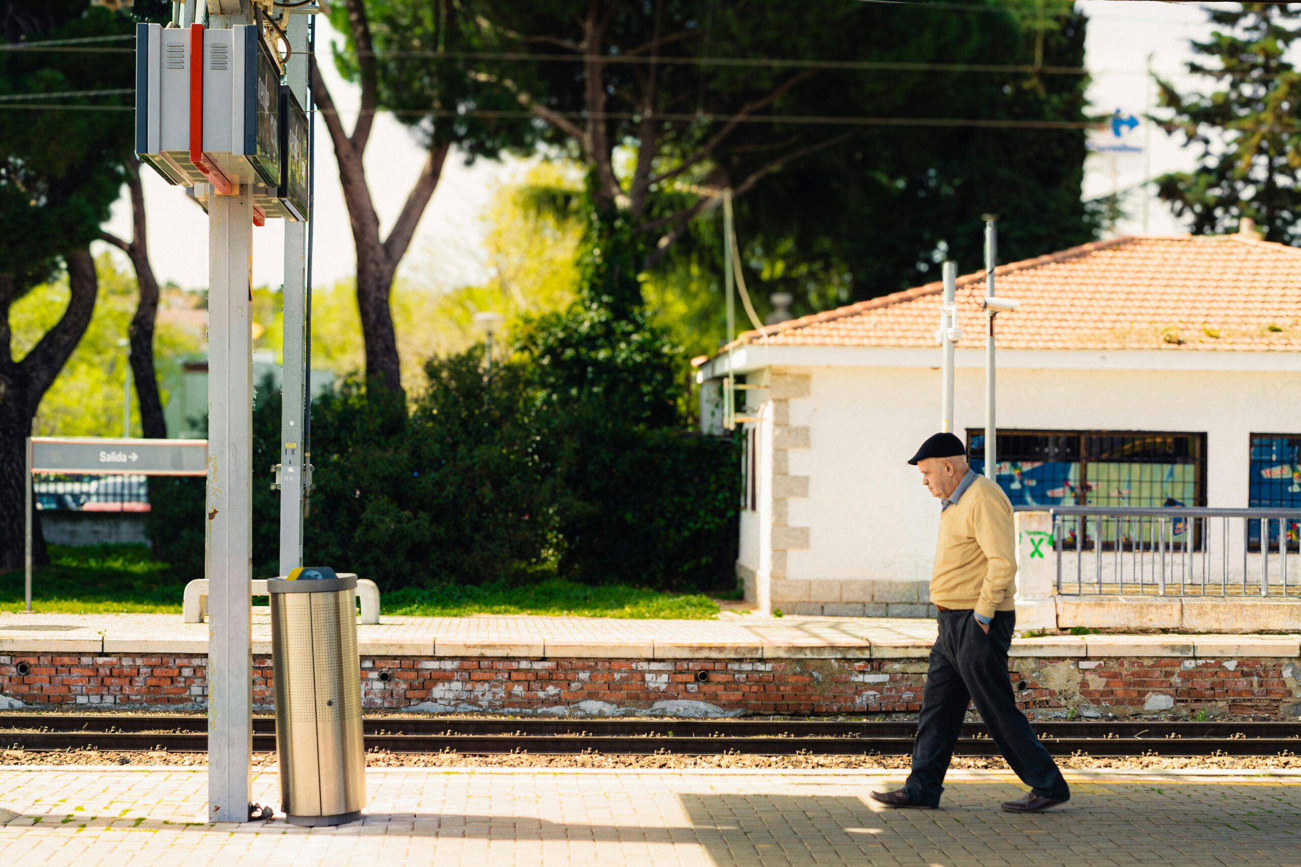 Senior man walking along a railway platform in Madrid, Spain, showcasing urban daily life.