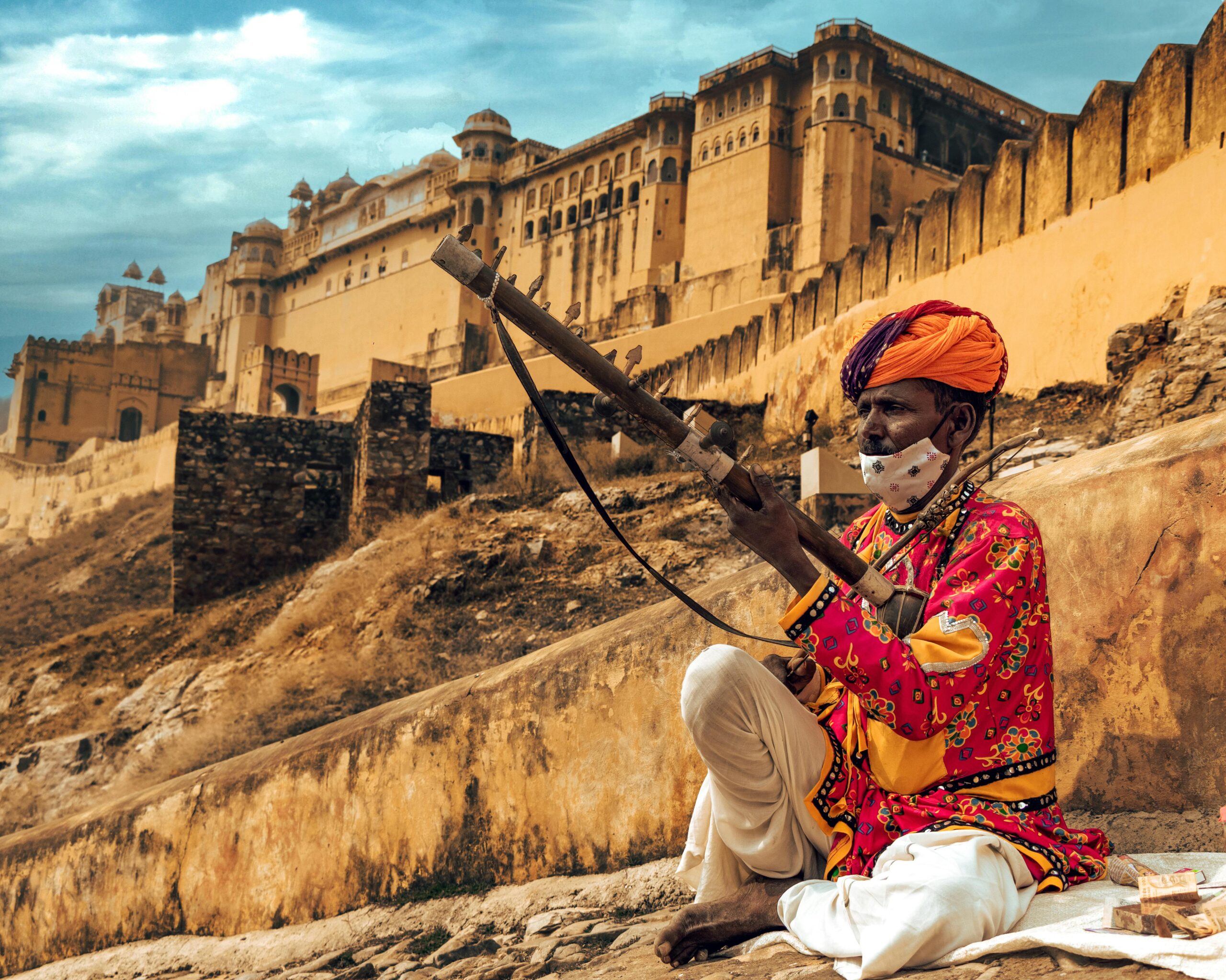 Traditional Rajasthani musician playing in front of the historic Amber Fort in Jaipur, India.