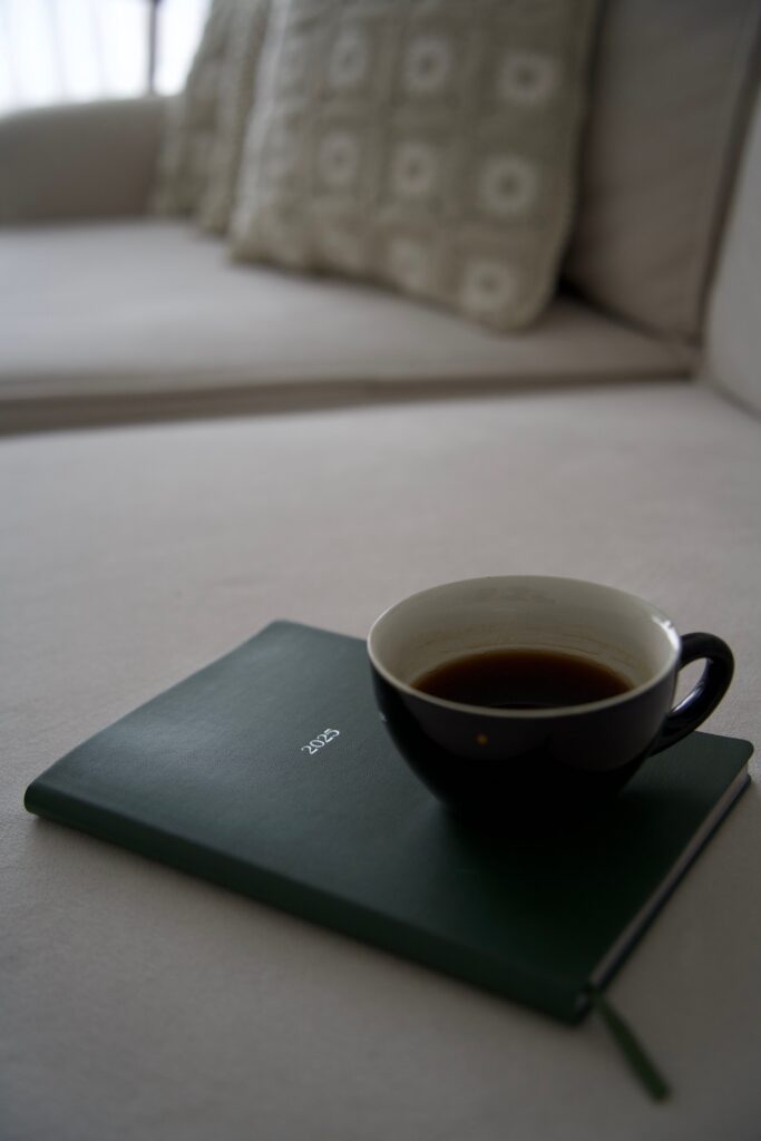 A serene indoor setting featuring a cup of black coffee resting on a green journal.